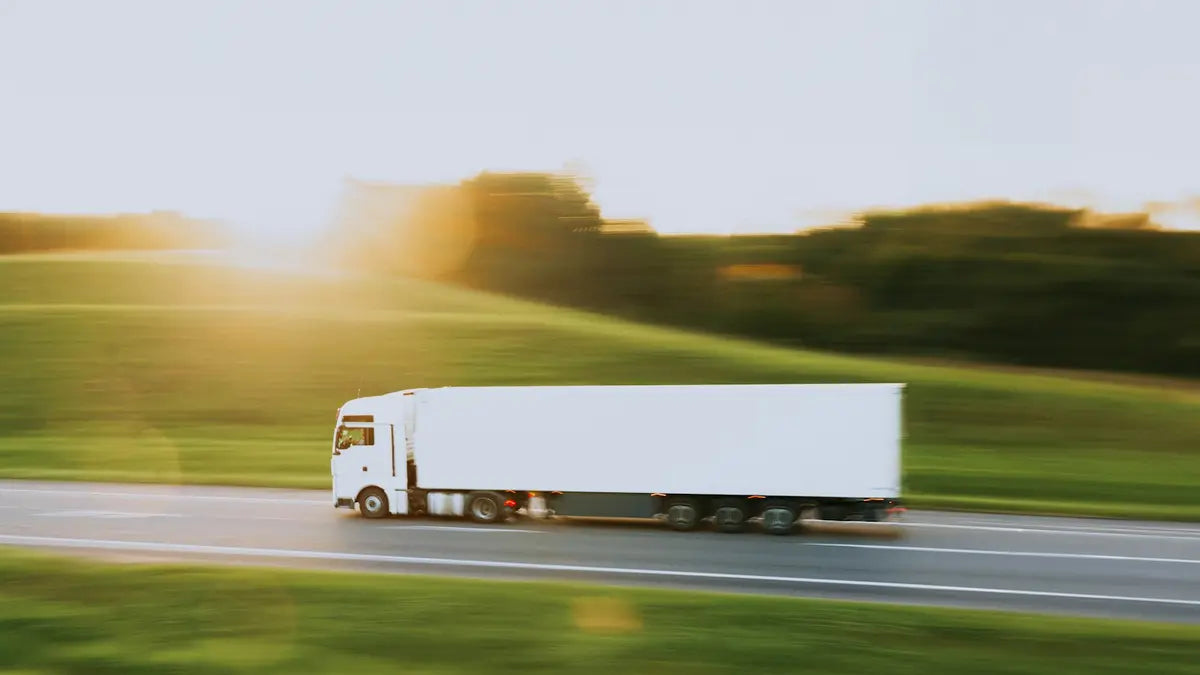 A plain white lorry on a road through green countryside.